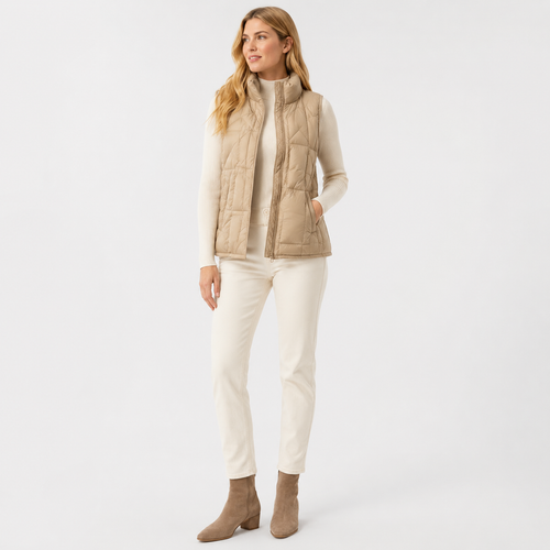 Woman wearing a beige women's lightweight puffer vest in a clean studio full-body view