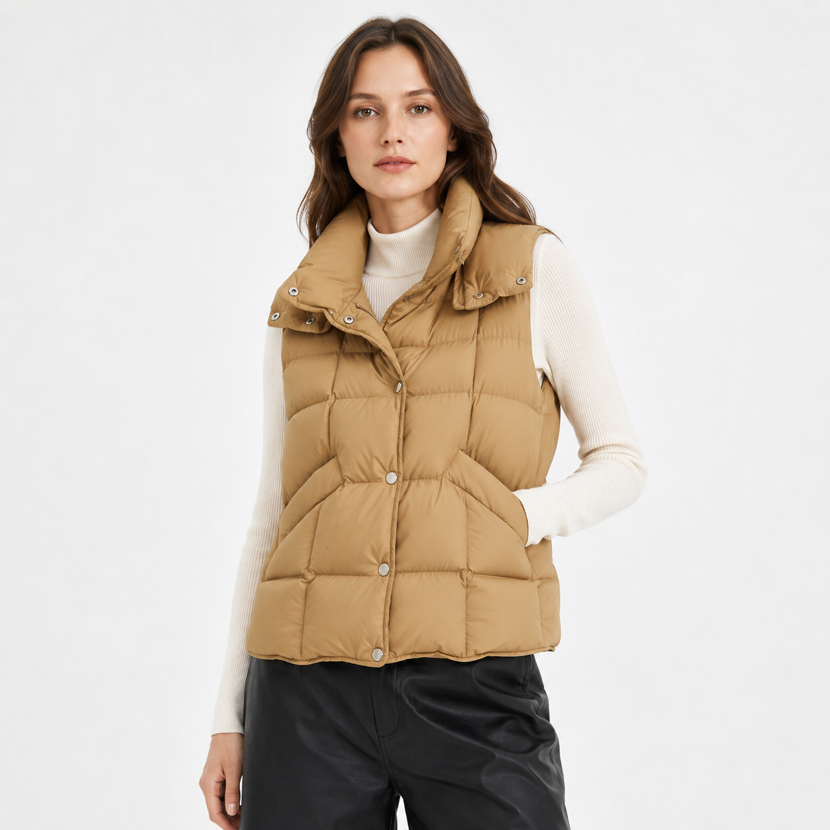 Woman wearing a camel women's high-collar puffer vest in a clean studio front view with cream knit top