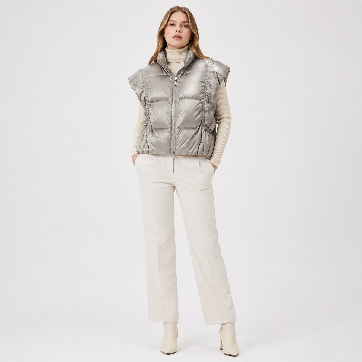 Woman wearing a metallic silver women's metallic high-collar puffer vest in a clean studio full-body view