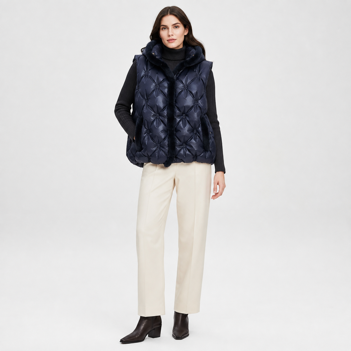Woman wearing a navy women's hooded quilted puffer vest in a clean studio full-body view