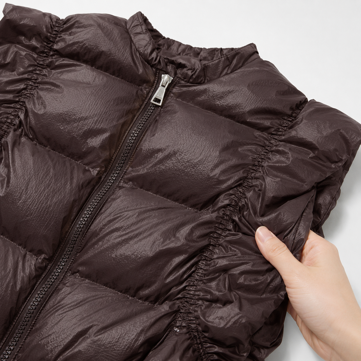 Close-up of high stand collar, zipper and gathered armhole on the metallic brown women's metallic high-collar puffer vest